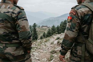 Two Indian Army officers in camouflage fatigues seen from behind, looking out over a mountain valley in a counter-insurgency zone.